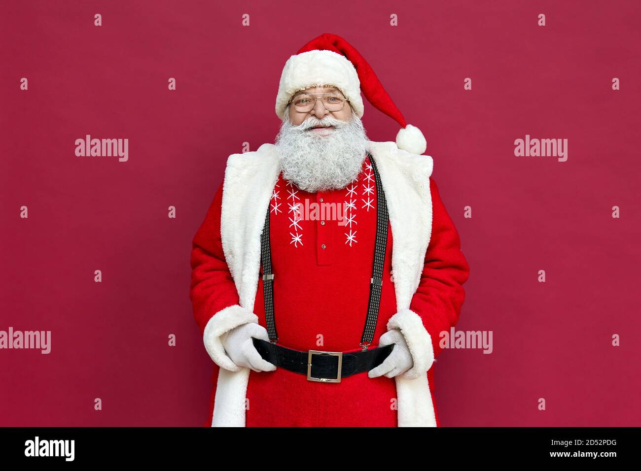 Portrait du vieux Père Noël heureux portant un costume isolé sur fond rouge. Banque D'Images