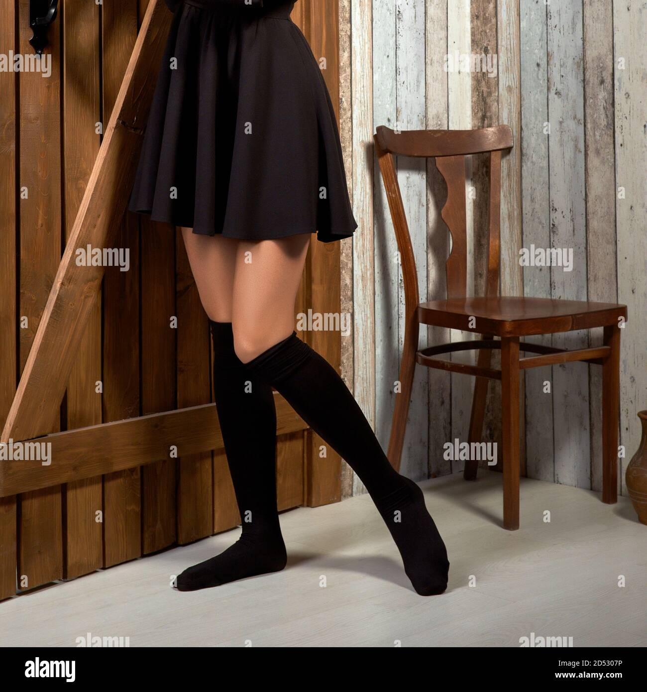 Jambes de femmes dans les chaussettes au-dessus du genou près de la porte en bois (l'image contient un peu de bruit) Banque D'Images