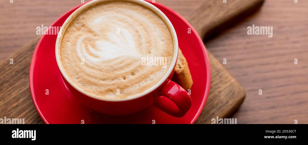 Latte Art, vue latérale du café chaud isolé sur fond de bois. Le matin avec une tasse de café ou de cappuccino rouge. Café d'art et d'artisanat. Bannière web Banque D'Images