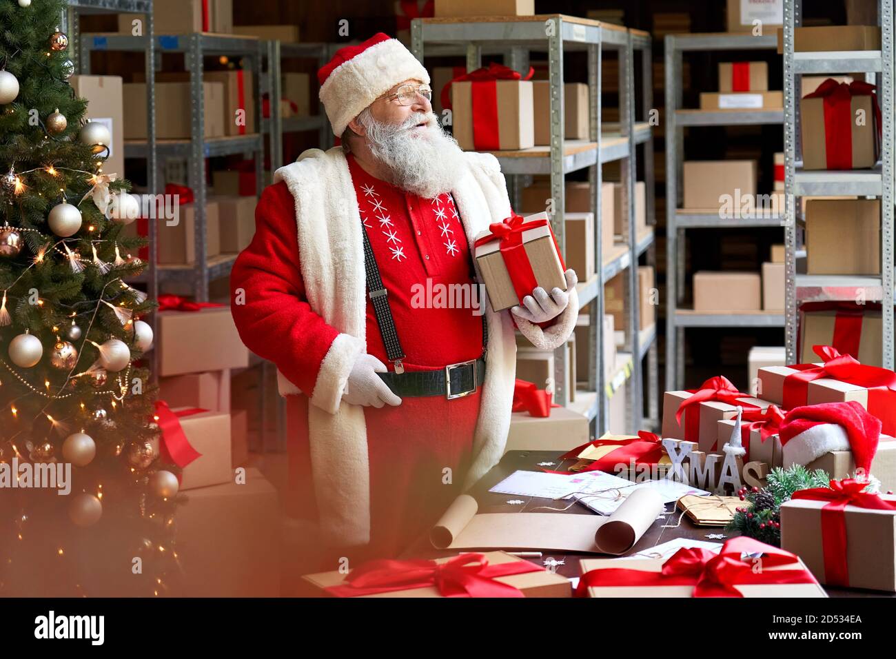 Santa Claus tenant présente boîte cadeau préparation pour Noël debout dans l'atelier. Banque D'Images