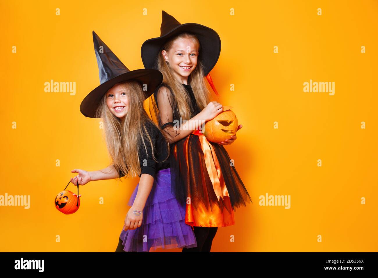 Portrait de deux petites filles drôles vêtues comme halloween basculer sur fond orange Banque D'Images