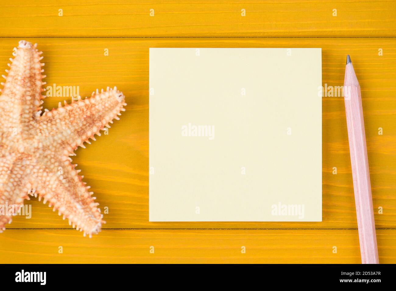 Vue de dessus de la tête gros plan rognée photo d'étoiles de mer vierge note et crayon isolés sur fond en bois jaune avec espace de copie Banque D'Images