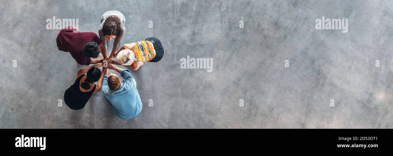 Vue de dessus du groupe de jeunes de mettre leurs mains ensemble. Les jeunes élèves debout dans un cercle faisant pile de mains montrant le succès. Banque D'Images