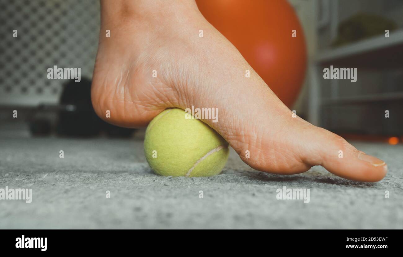 Femme massant son pied avec une balle de tennis Photo Stock - Alamy