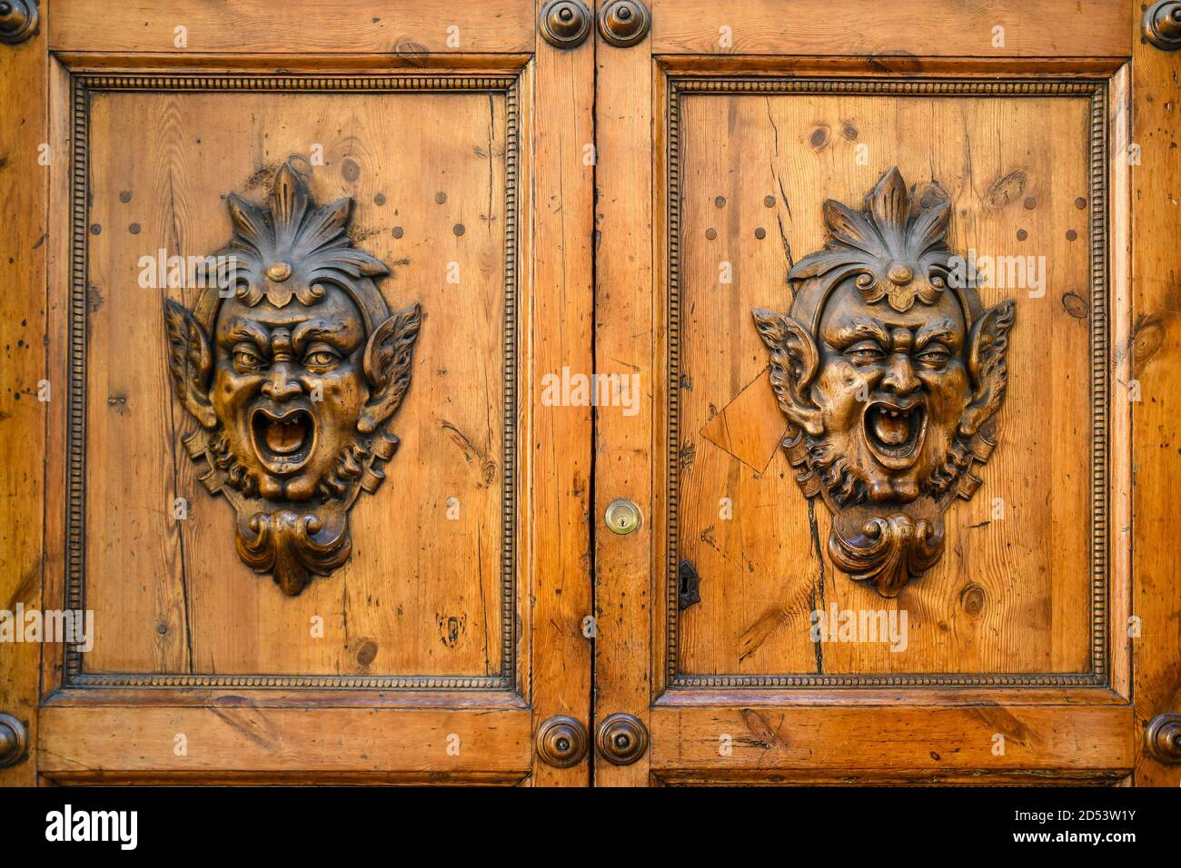 Vue rapprochée d'une ancienne porte en bois sculptée avec la tête du démon ou des gargouilles dans le centre historique de Sienne, Toscane, Italie Banque D'Images