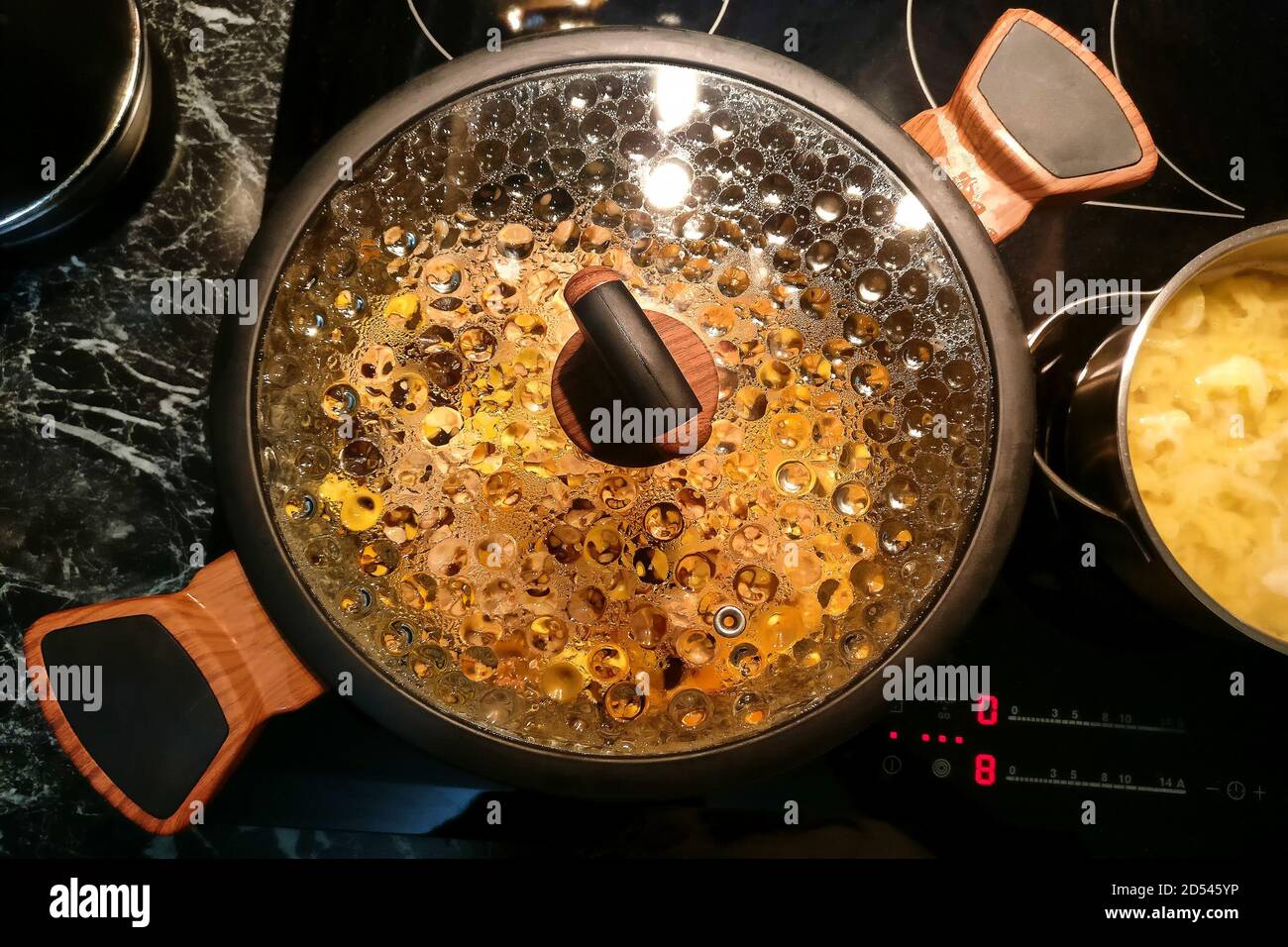 Faites une casserole sur la cuisinière avec de la condensation sur le couvercle en verre, gros plan Banque D'Images