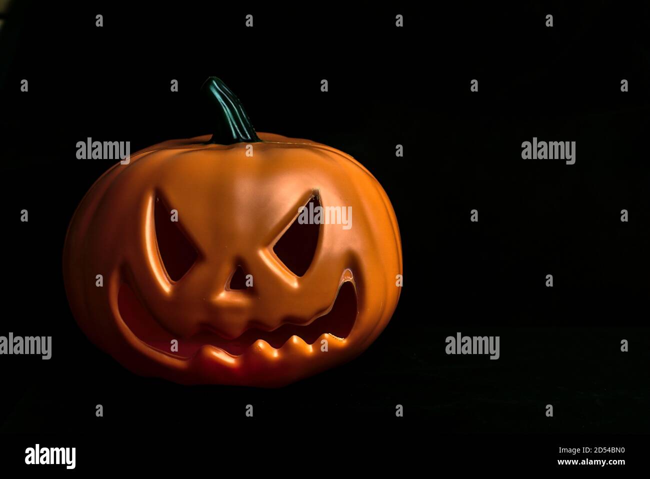 Citrouille orange Halloween en plastique isolé avec visage effrayant arrière-plan noir avec espace de copie Banque D'Images