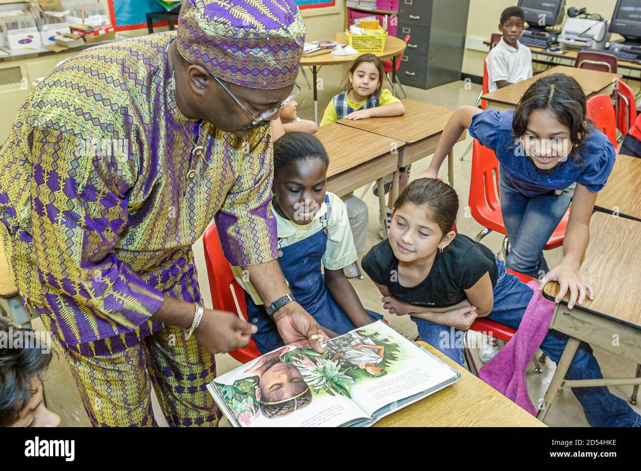 Miami Florida,Overtown,Frederick Douglass Elementary School,professeur homme tenue habillée, littéraire costume lecture livre caractère fictif, hispanique Banque D'Images