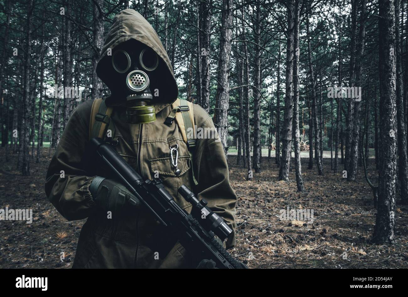 Photo d'un soldat de la guerre nucléaire debout et posant dans un masque à gaz soviétique, sac à dos avec fusil en bois. Banque D'Images