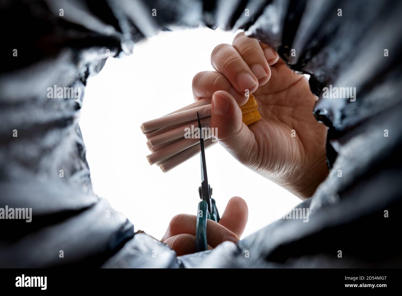 homme coupant un bouquet de cigarettes par une paire de ciseaux sur le dessus d'un concept de poubelle de cesser de fumer Banque D'Images