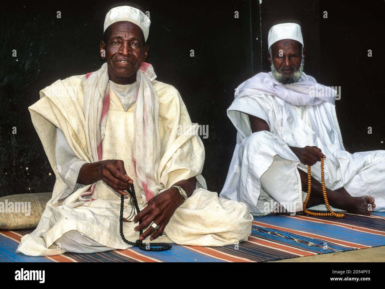 Bouake, Côte d'Ivoire, Côte d'Ivoire. Musulmans ivoiriens avec des perles de prière se détendre en attendant le temps de prière à l'extérieur de la mosquée. Banque D'Images