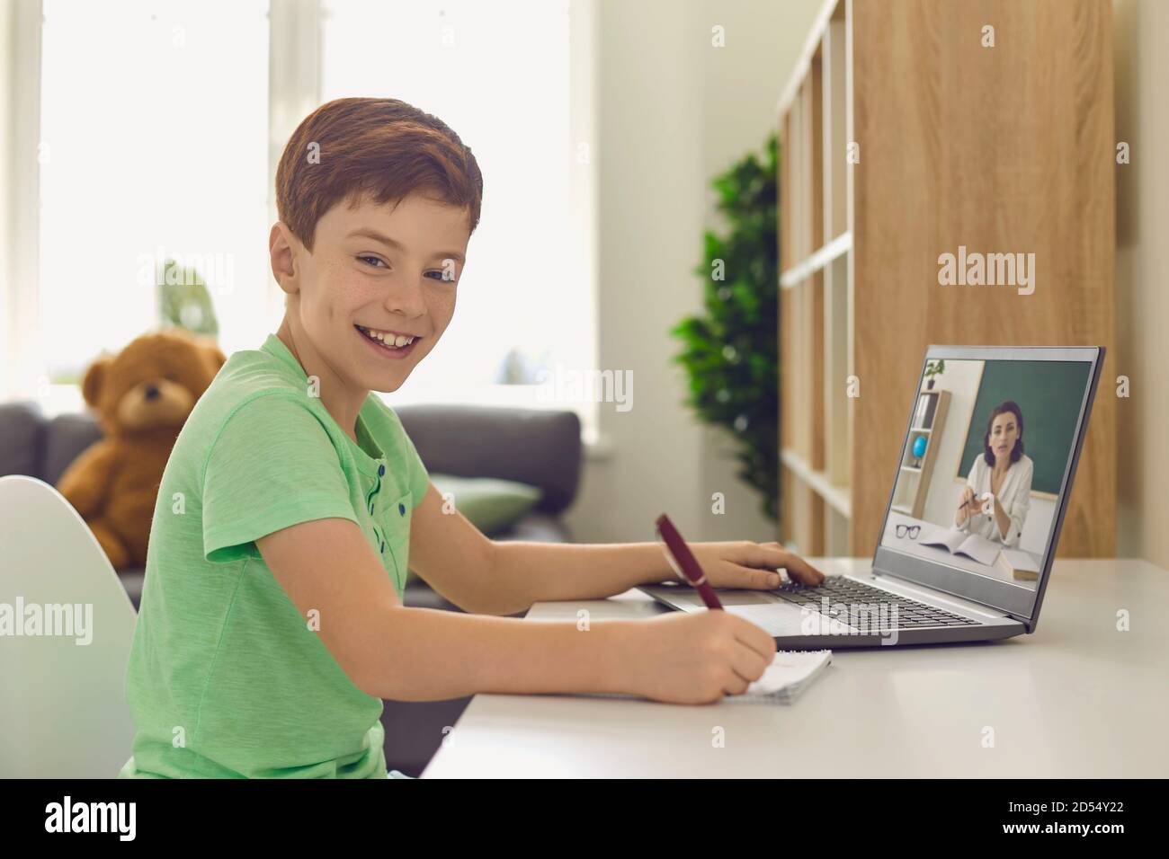 Garçon souriant étudiant à la maison via un ordinateur portable Banque D'Images