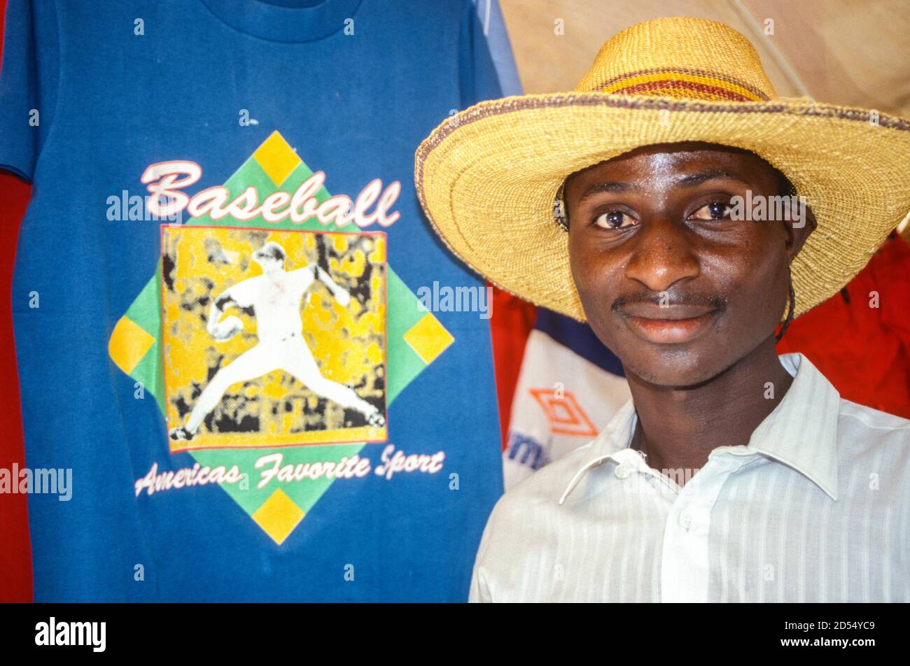 Boubon, Niger. Fournisseur de vêtements d'occasion avec un t-shirt de baseball américain. Banque D'Images