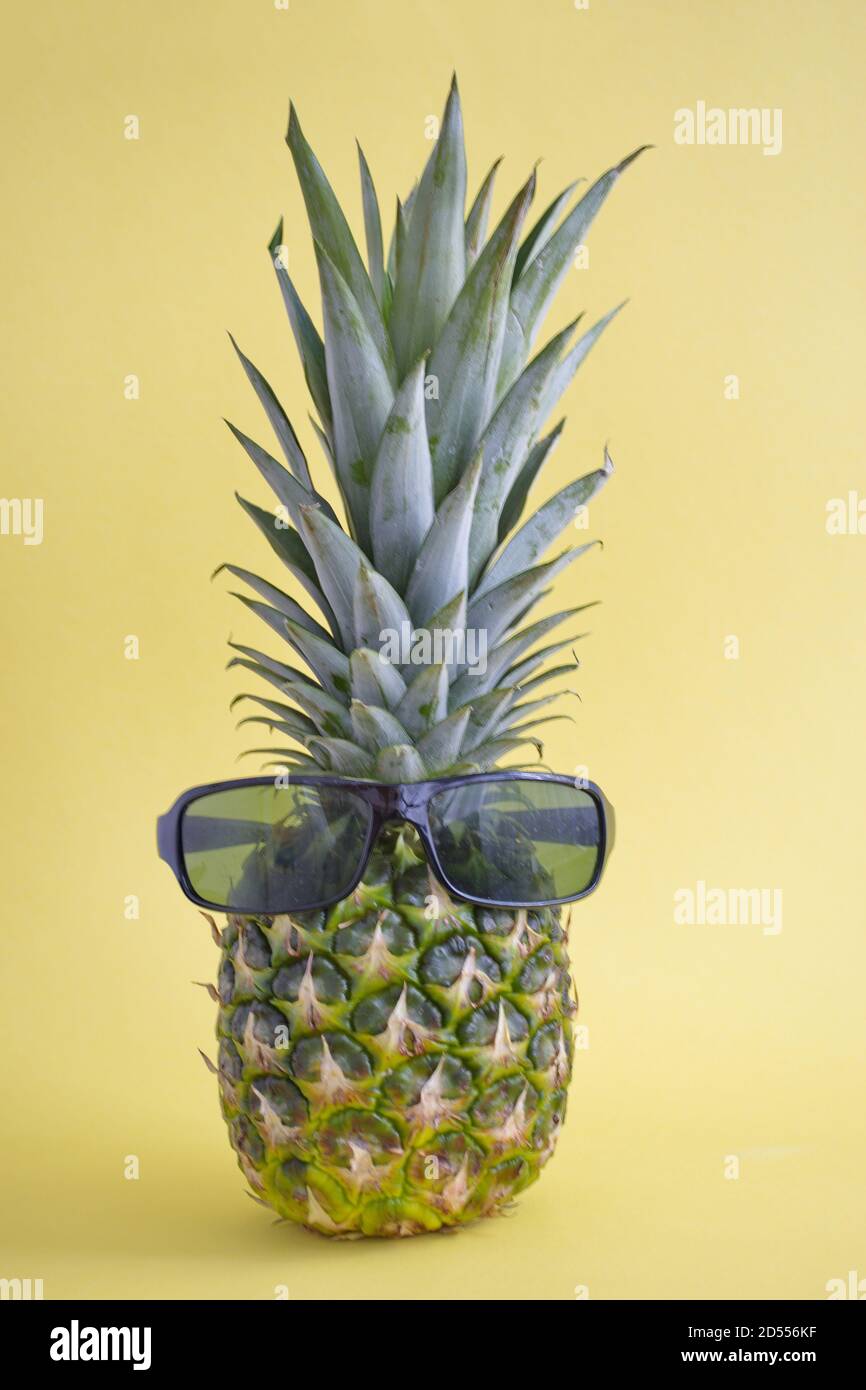 Ananas mûr avec lunettes de soleil sur fond jaune Banque D'Images