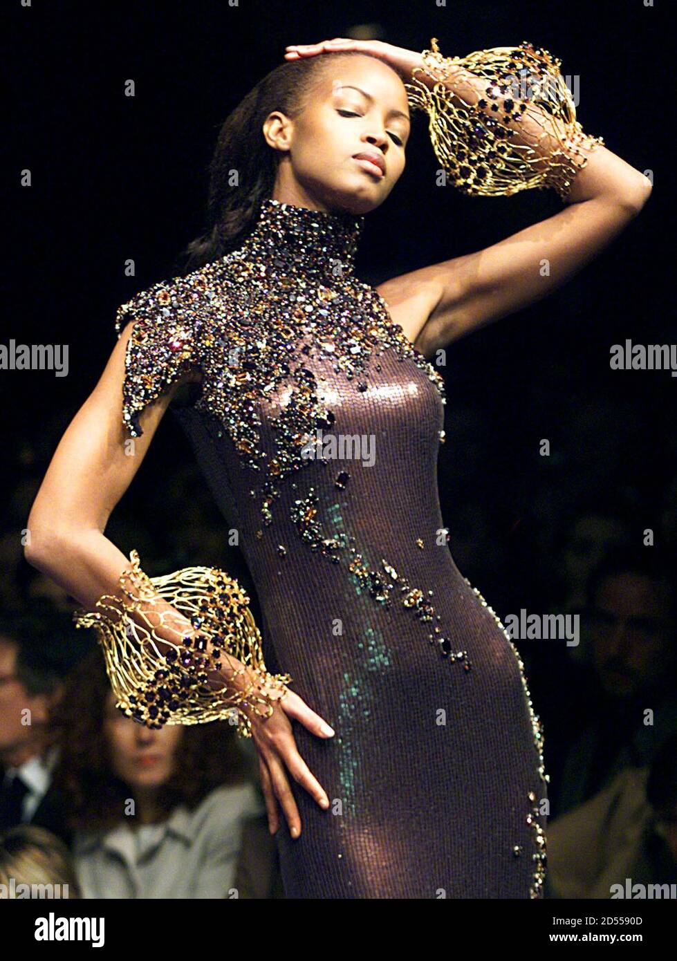 Un modèle pour la maison de mode française Jean-Louis Scherrer, conçu par  Stephane Rolland, présente cette robe de style marron incrustée de bijoux  avec des manchettes dorées dans le cadre de sa