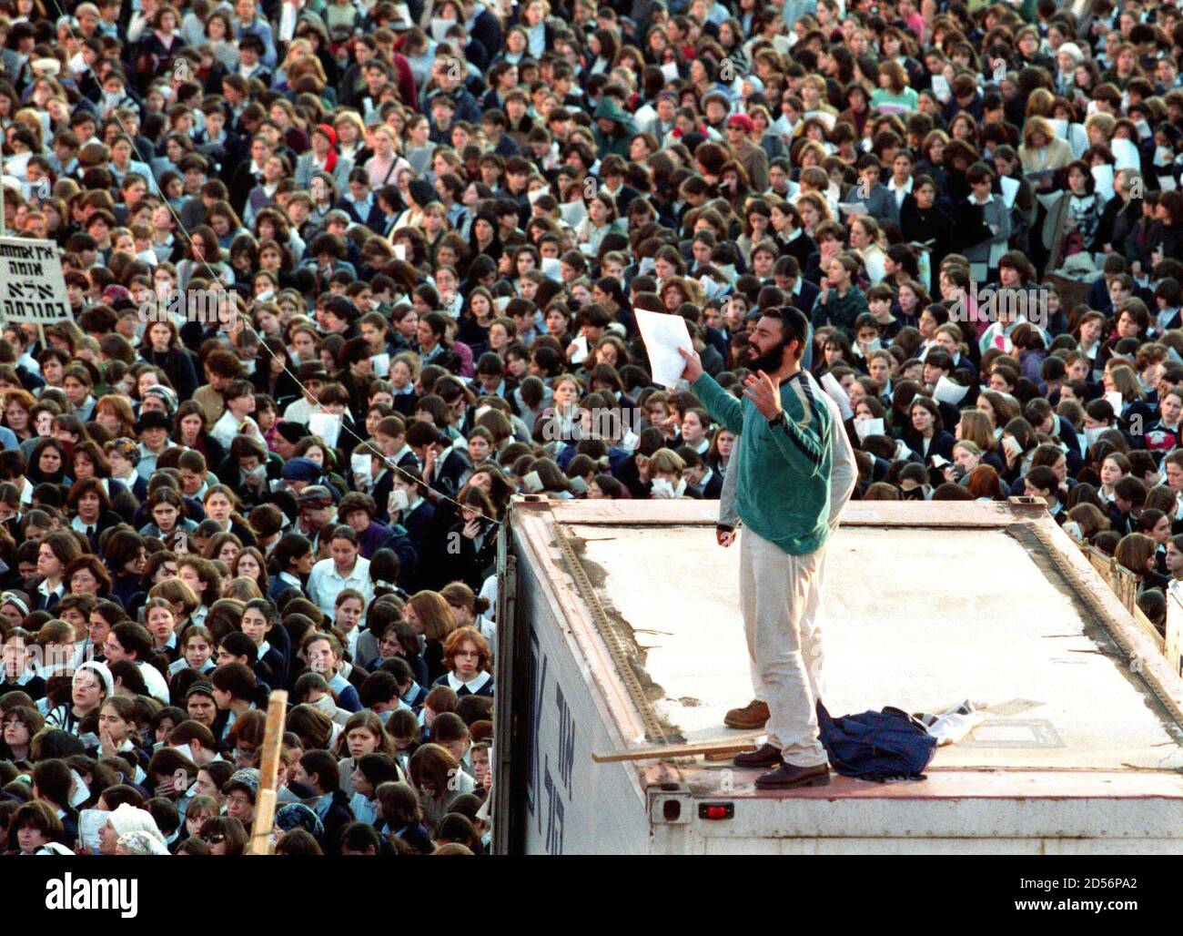 A religious Jew lifts his arms as he 