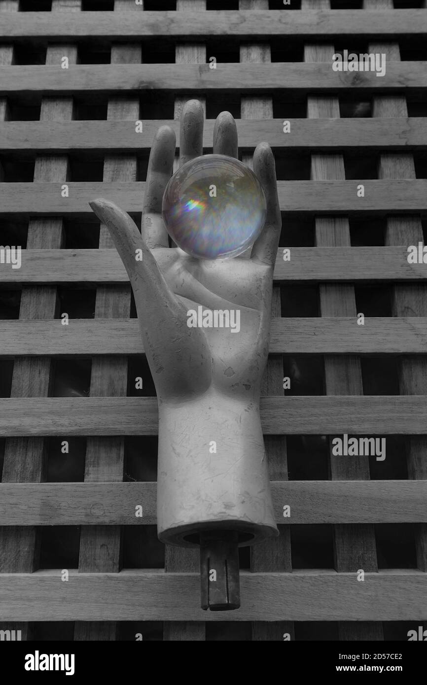 Vieille poupée mannequin tenant main boule de cristal avec des reflets colorés. Visions de l'avenir. Banque D'Images