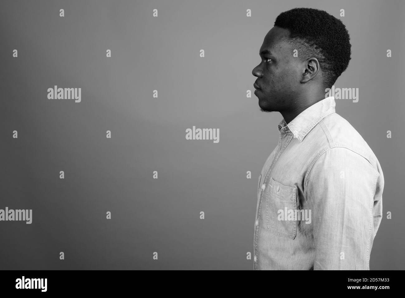 Young African man wearing denim shirt contre l'arrière-plan gris Banque D'Images