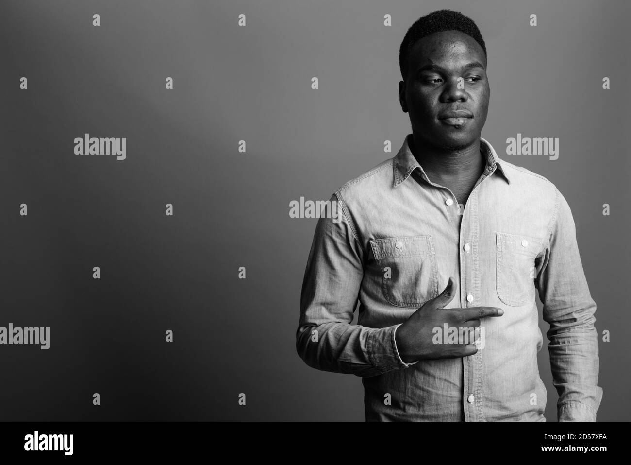 Young African man wearing denim shirt contre l'arrière-plan gris Banque D'Images