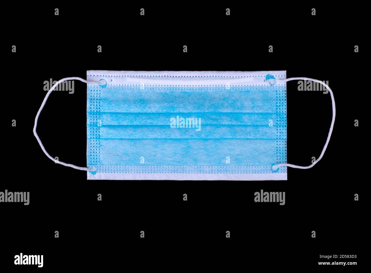 Masque médical bleu isolé sur fond noir. Pose à plat. Banque D'Images