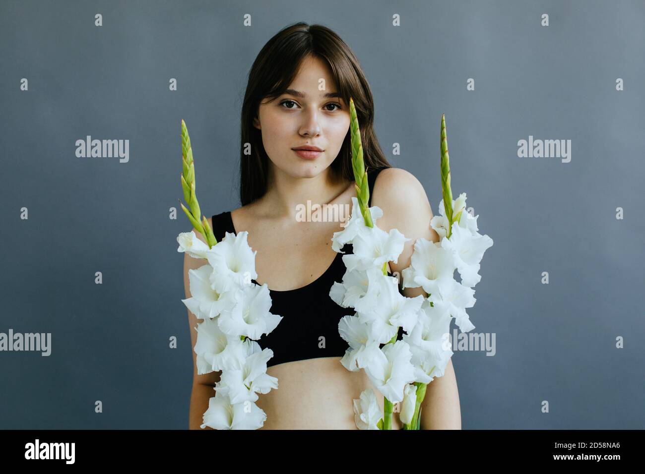 Portrait d'une belle femme tenant trois fleurs gladioli blanches Banque D'Images