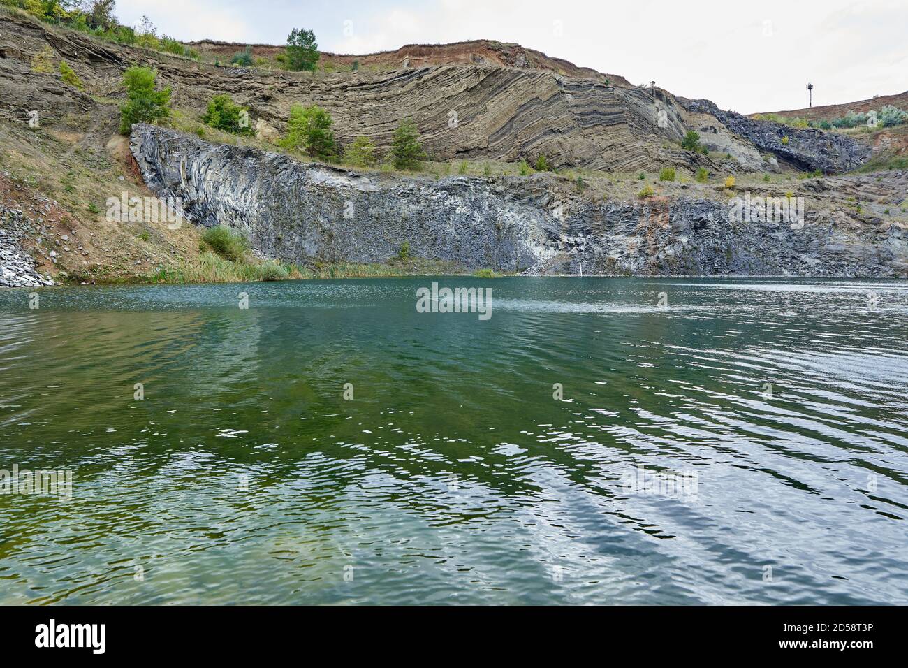 Paysage avec un lac formé dans une ancienne carrière avec roches sédimentaires et couches géologiques visibles Banque D'Images