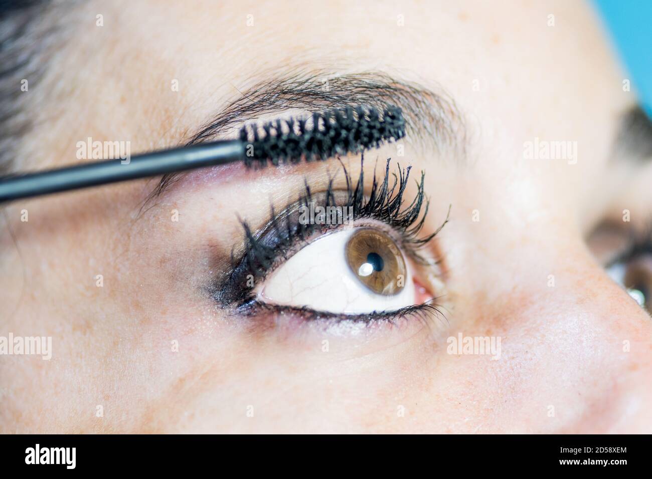 Gros plan de l'œil d'une jeune femme en profil mettre sur le maquillage avec mascara pour cils Banque D'Images