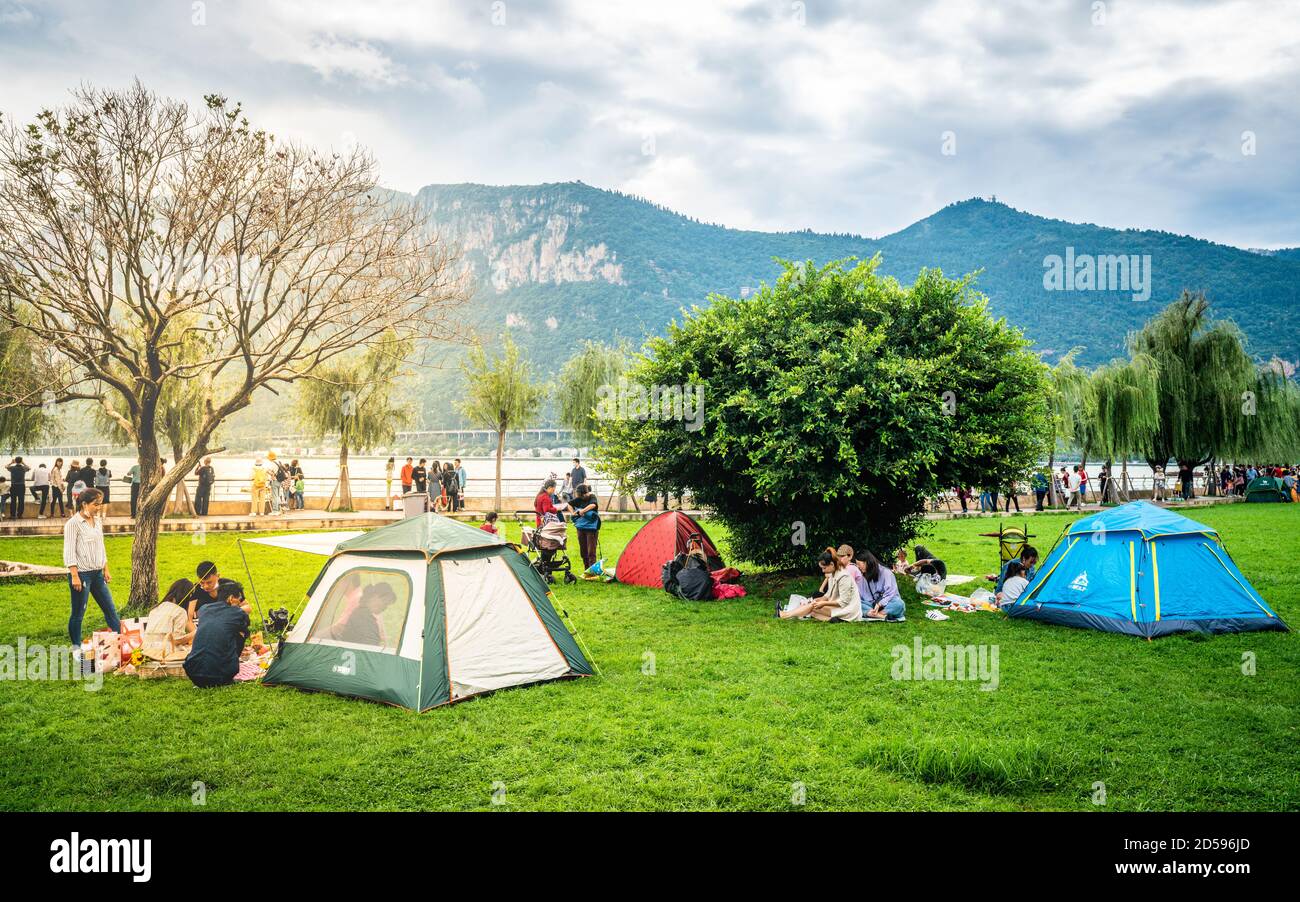 Kunming Chine , 3 octobre 2020 : Chinois appréciant des vacances dans le parc de Dianchi Haigeng avec des tentes sur l'herbe et le lac et les collines de l'ouest dans backgr Banque D'Images