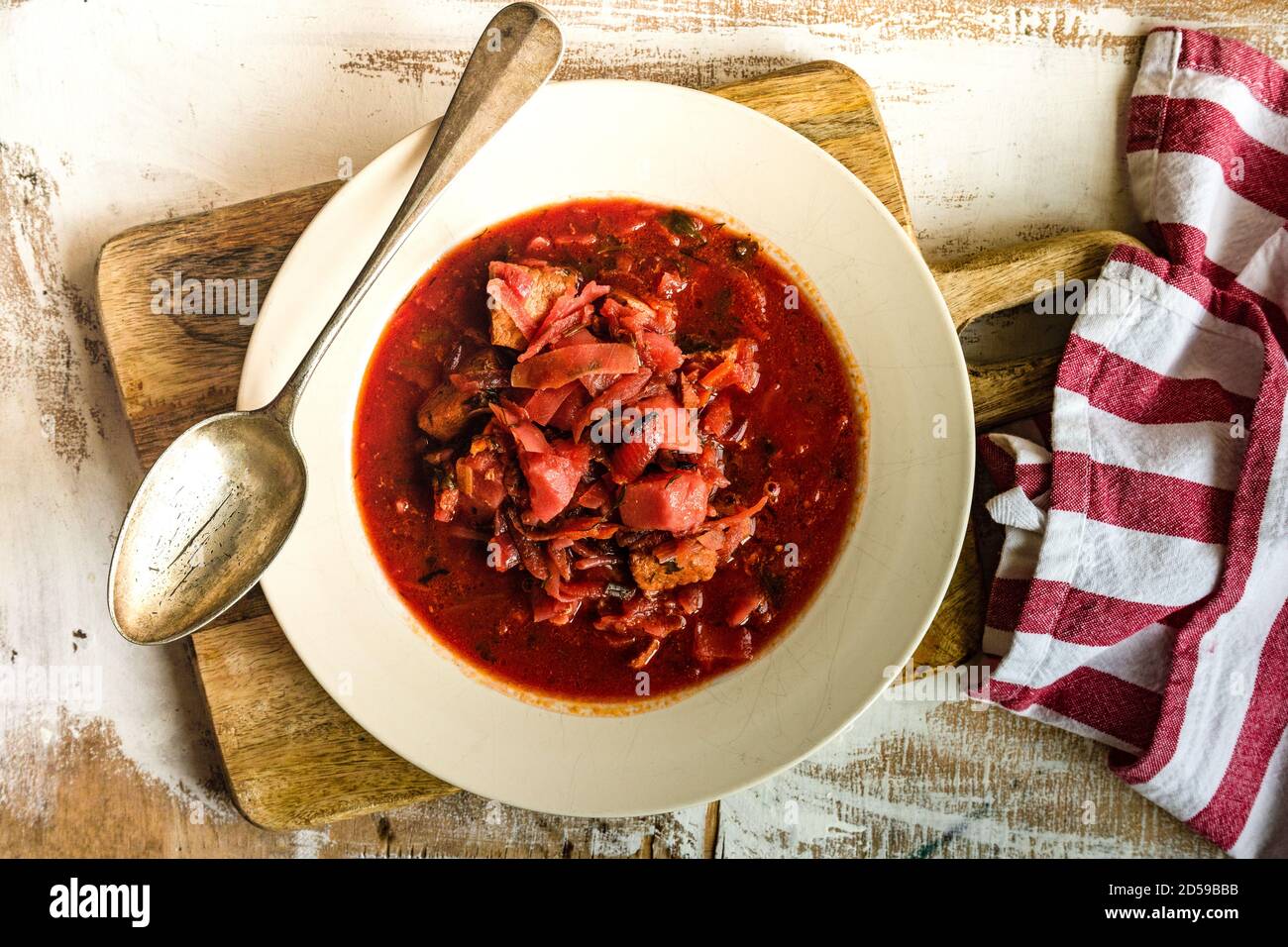 Vue en hauteur d'un bol de soupe de betteraves ukrainiennes une planche à découper en bois Banque D'Images