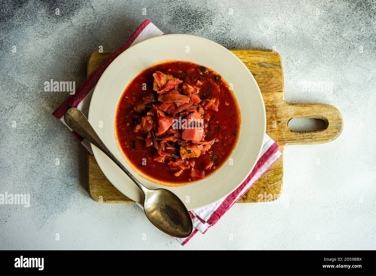 Vue en hauteur d'un bol de soupe de betteraves ukrainiennes une planche à découper en bois Banque D'Images