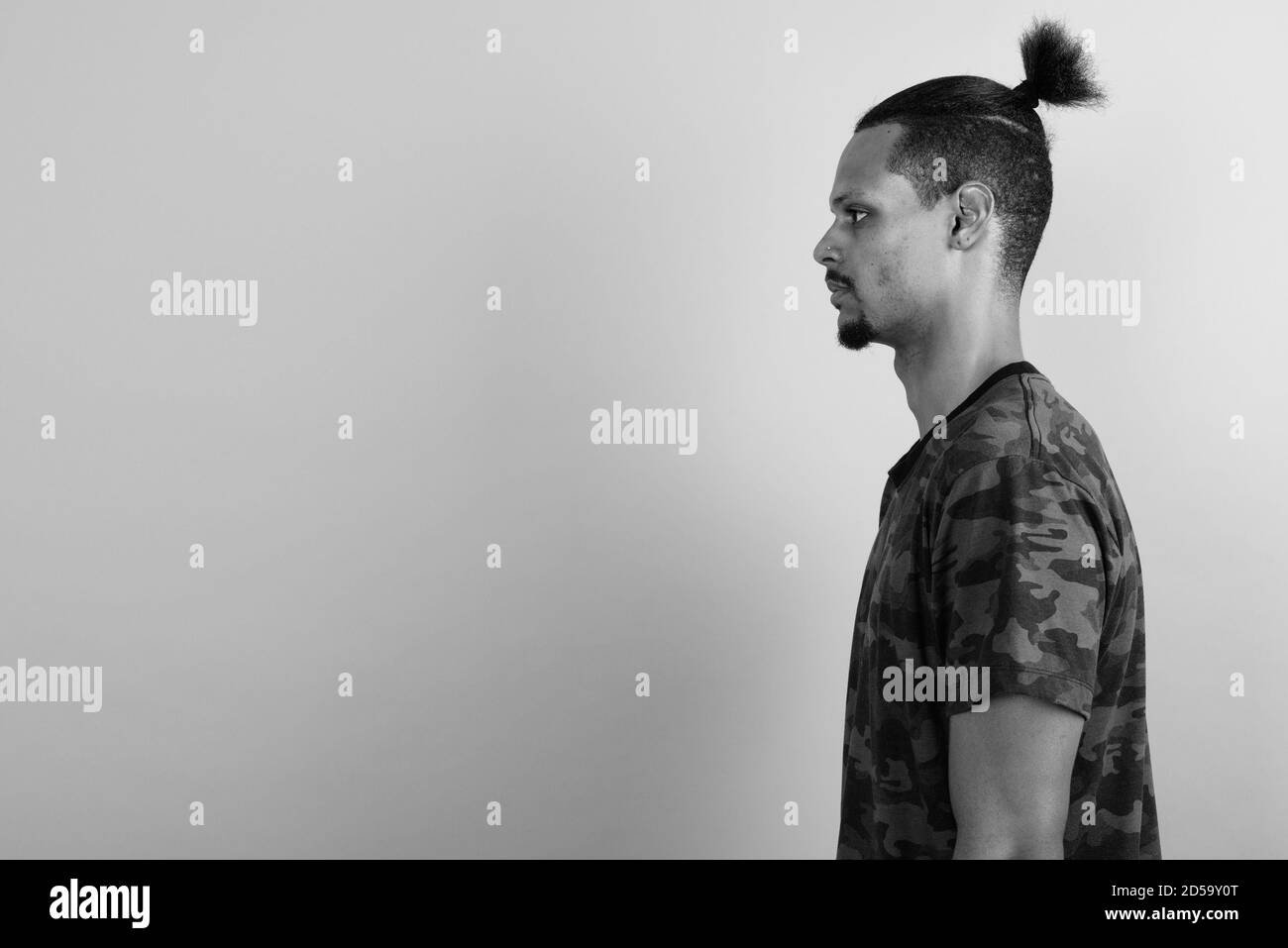 Beau jeune homme barbu africain contre l'arrière-plan gris Banque D'Images