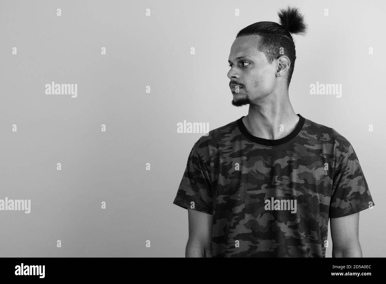 Beau jeune homme barbu africain contre l'arrière-plan gris Banque D'Images