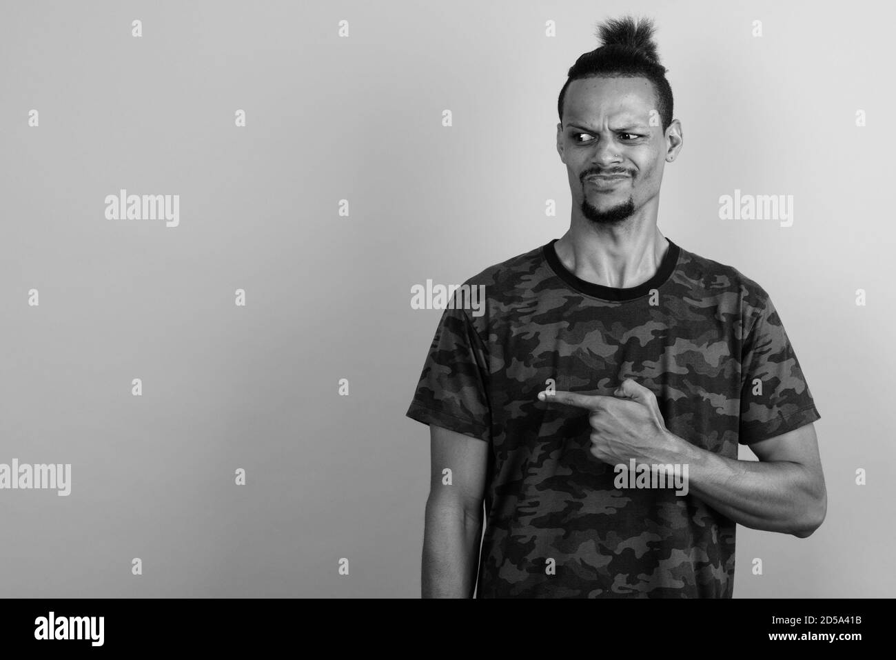 Beau jeune homme barbu africain contre l'arrière-plan gris Banque D'Images