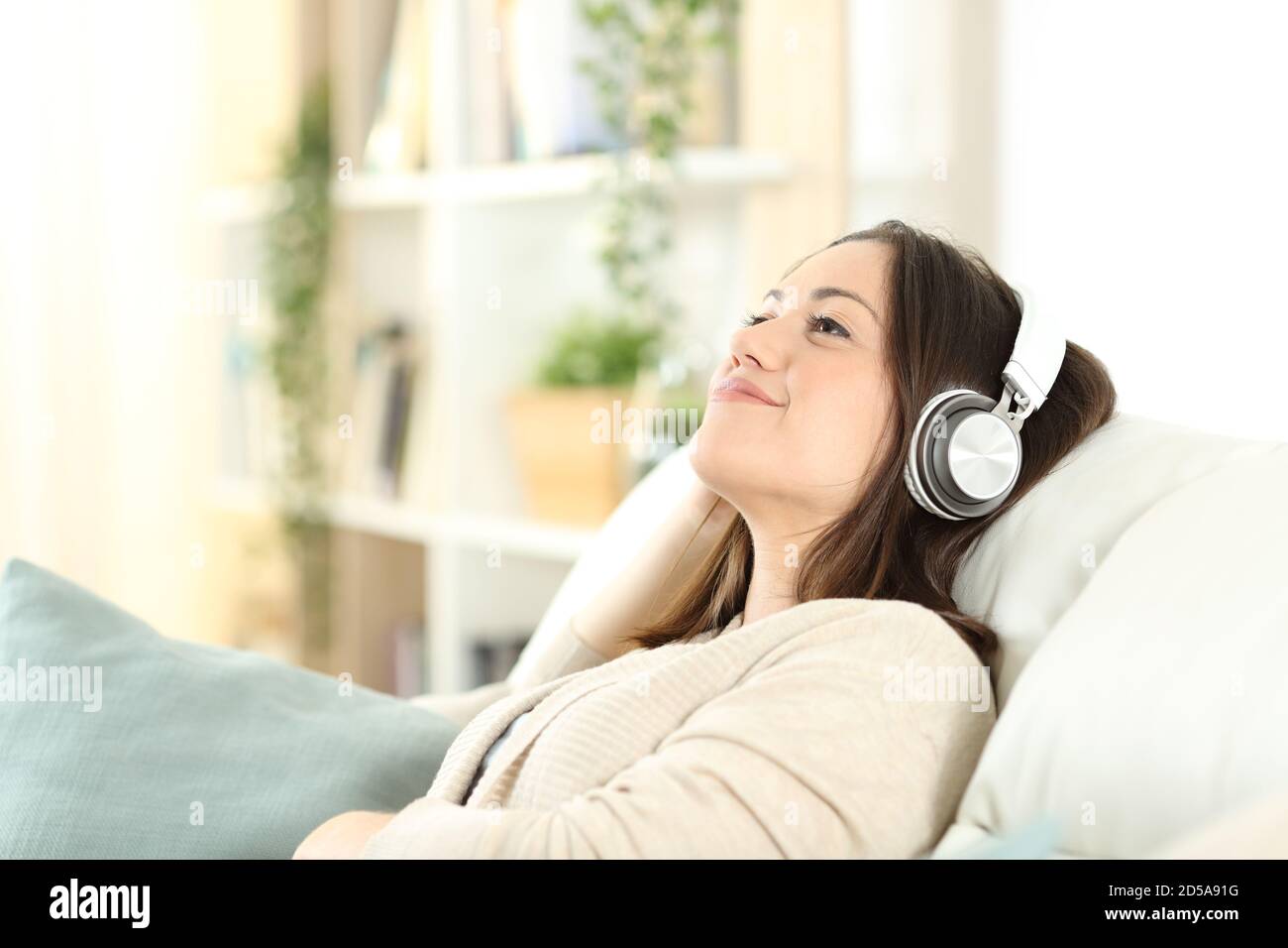 Une femme satisfaite se détendant sur un canapé pour écouter de la musique à la maison Banque D'Images