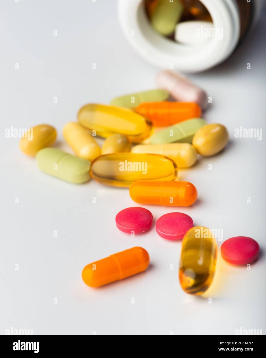 Assortiment de pilules de médecine pharmaceutique qui se répandent hors d'une bouteille Un arrière-plan blanc Banque D'Images