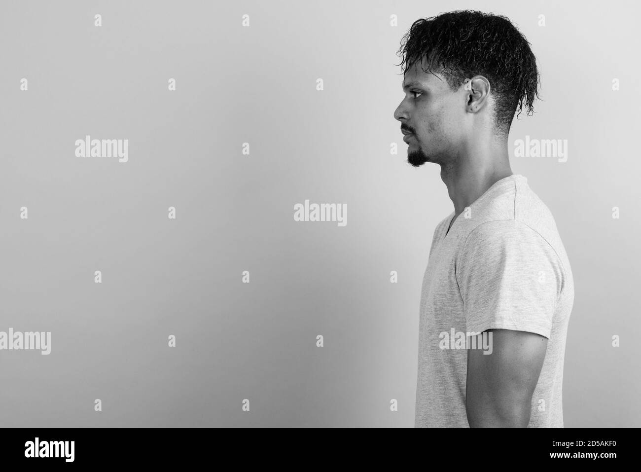 Beau jeune homme barbu africain contre l'arrière-plan gris Banque D'Images