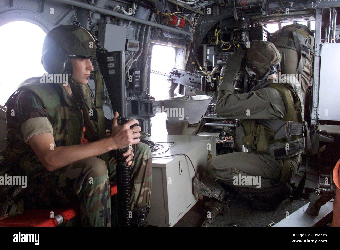 Un Marine américaine de la 26e unité expéditionnaire maritime (MEU) tient son riflle d'assaut M-16 comme un crewman d'un hélicoptère CH-46 Sea Knight prend position par un machinegun de calibre 50 mm lors d'une mission au-dessus de l'Albanie mai 9. L'élément de combat d'aviation (ACE) du 26e MEU comprend 12 hélicoptères de transport CH-46E Sea Knight, quatre hélicoptères de levage lourd CH-53E Super Stallion, quatre hélicoptères de combat AH-1W Super Cobra, deux hélicoptères DE transport UH-1N et six avions d'attaque AV-8B Harrier. YB/AS Banque D'Images