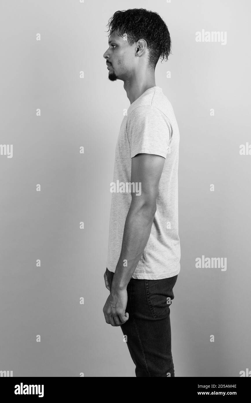 Beau jeune homme barbu africain contre l'arrière-plan gris Banque D'Images