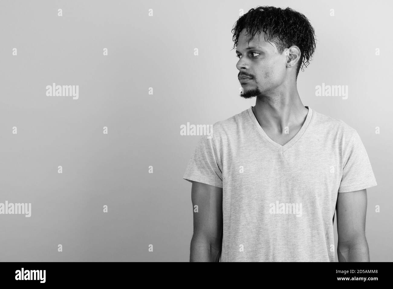 Beau jeune homme barbu africain contre l'arrière-plan gris Banque D'Images