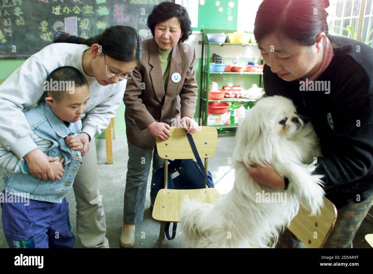 A Chinese volunteer encourages a mentally handicapped boy (L) to play with  a one and half-year-old 