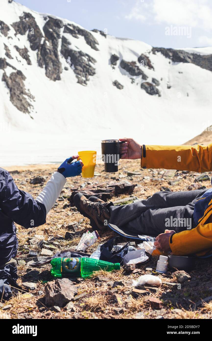 Image de POV de couple tenant des tasses sur le sommet de la montagne, boire le thé et le café des mugs touristiques, assis près de l'équipement de camping, Voyage aventure style de vie conce Banque D'Images