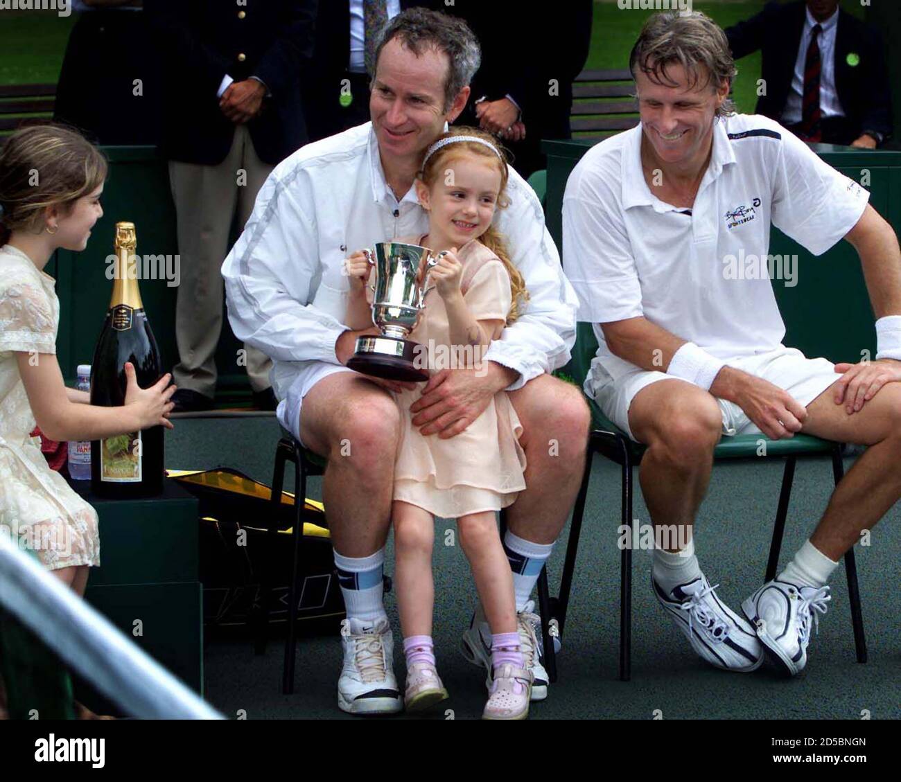 Anna (C), fille de John McEnroe, détient le trophée de son père tandis que  son autre fille Emily (L) lui apporte du champagne après sa victoire sur Bjorn  Borg (R) après leur