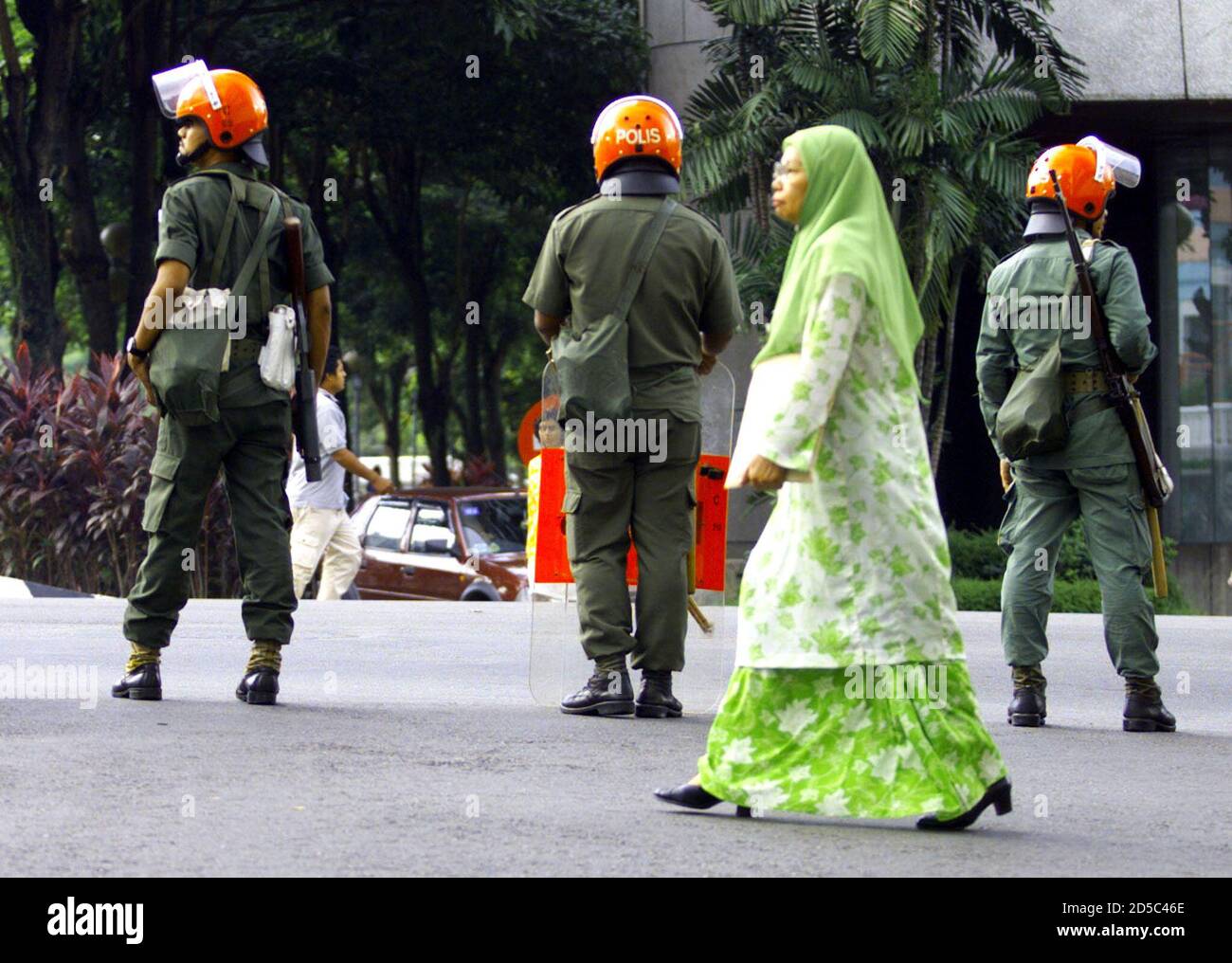 Une femme malaisienne se promène derrière la police anti-émeute près du palais de justice où le procès criminel d'Anwar Ibrahim a eu lieu le 2 novembre. Anwar a été renvoyé au poste de vice-premier ministre et ministre des Finances le 2 septembre et arrêté 18 jours plus tard, après avoir conduit 30,000 manifestants anti-gouvernement à se hantir dans les rues de la capitale et de la place Merdeka. Il a ensuite été inculpé de 10 chefs d'accusation de corruption et de sodomie dont il a plaidé non coupable. CC/JO/SB Banque D'Images