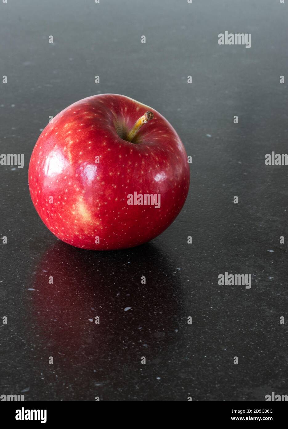 Une pomme par jour garde le médecin loin. Une pomme rouge savoureuse et fine sur fond sombre, table de cuisine. Une collation saine et une alimentation saine Banque D'Images