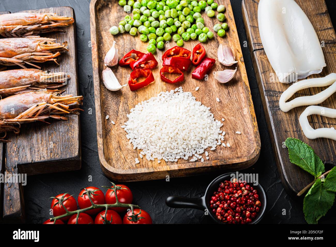 Ingrédients frais de paella non cuits avec crevettes géantes, moules et calmars sur fond noir texturé Banque D'Images