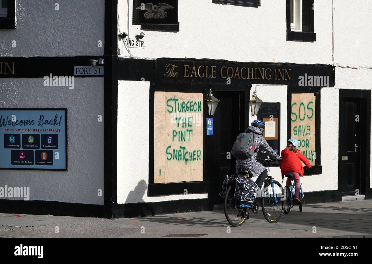 Les membres du cycle public ont passé l'Eagle Coaching Inn à Broughty Ferry, où des graffitis ont été écrits à l'embarquement au-dessus des fenêtres après l'entrée en vigueur d'une série de nouvelles restrictions visant à lutter contre l'augmentation des cas de coronavirus en Écosse. Banque D'Images