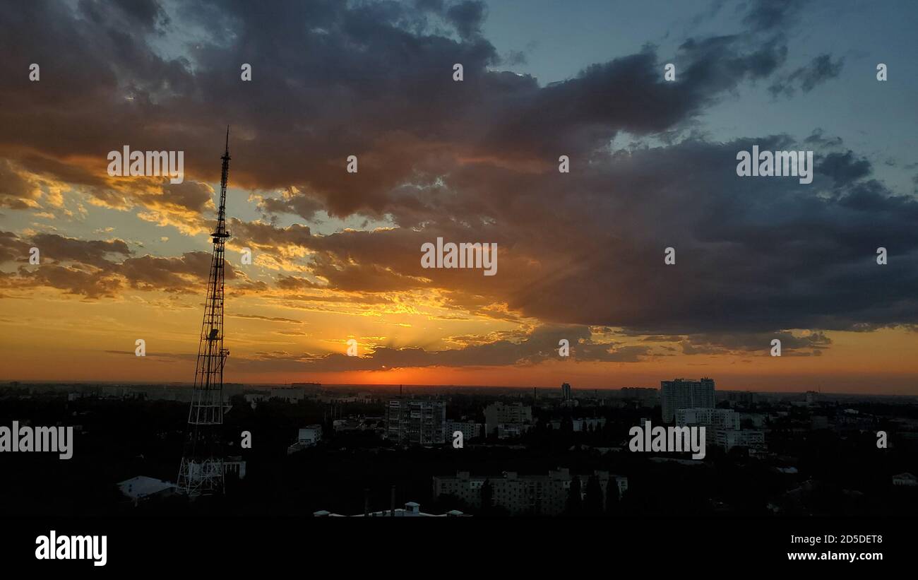 Coucher de soleil spectaculaire sur la ligne d'horizon urbaine avec silhouette de tour 5G. Nuages d'or sur fond ciel couvert Banque D'Images