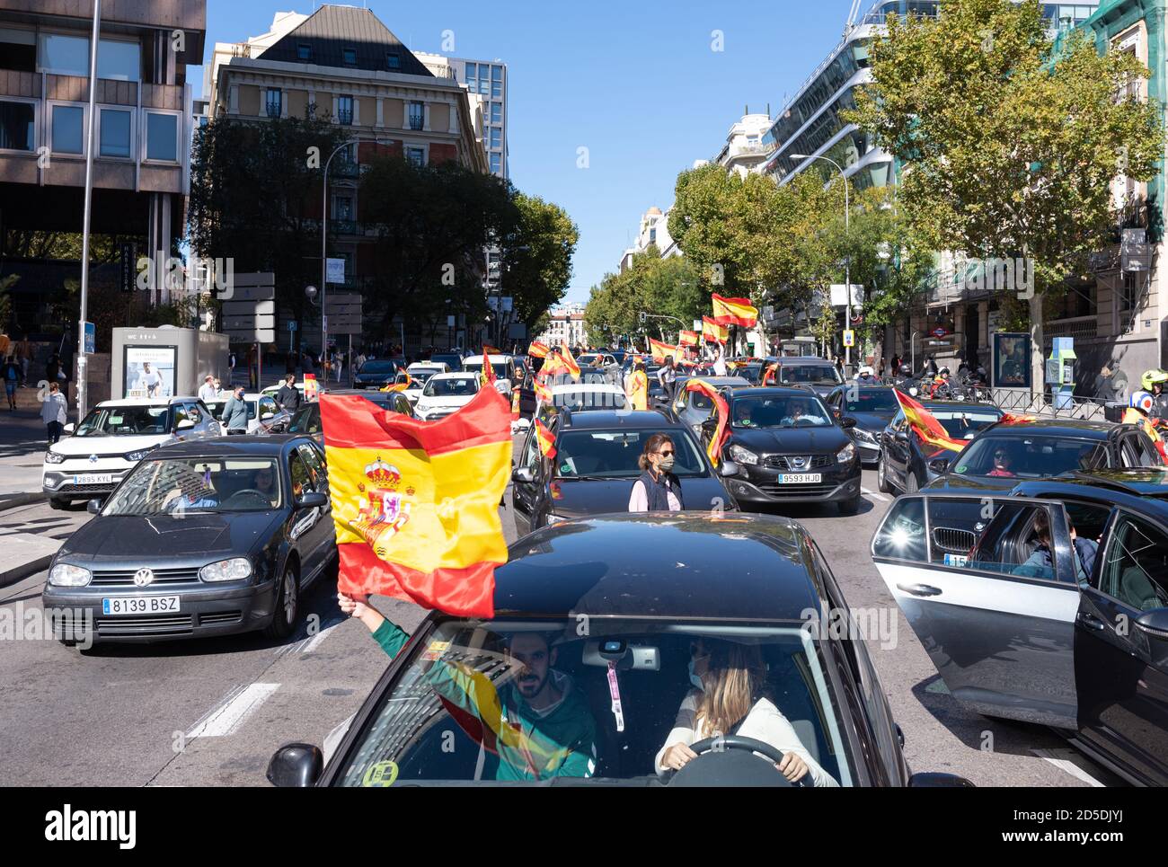 Madrid, Espagne, 12 octobre 2020. Des gens agitant le drapeau alors qu'ils assistent à un défilé de voitures protestent contre la gestion de la crise COVID-19 par le gouvernement espagnol. Banque D'Images