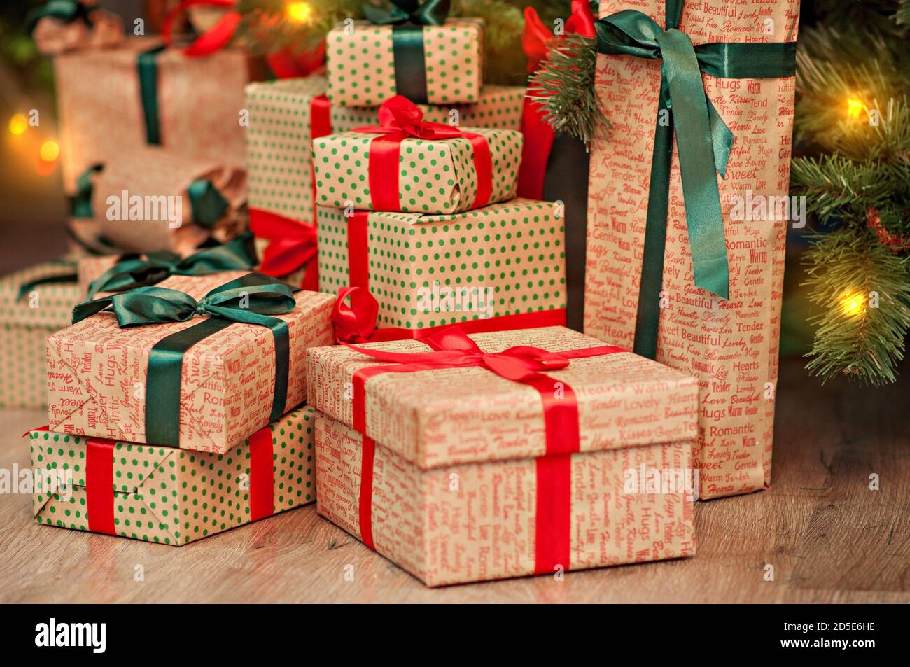 Une haute montagne de cadeaux sous un arbre de Noël dans des guirlandes de lumières en papier d'emballage d'artisanat rouge-vert avec boucles de ruban. Carte du nouvel an. Le Père Noël Banque D'Images