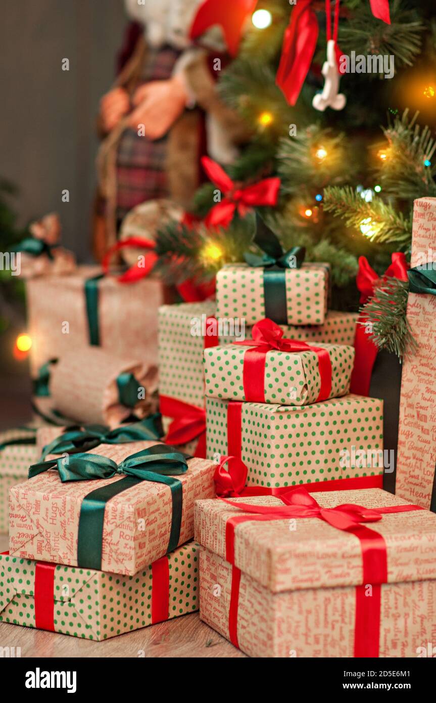 Une haute montagne de cadeaux sous un arbre de Noël dans des guirlandes de lumières en papier d'emballage d'artisanat rouge-vert avec boucles de ruban. Carte du nouvel an. Le Père Noël Banque D'Images